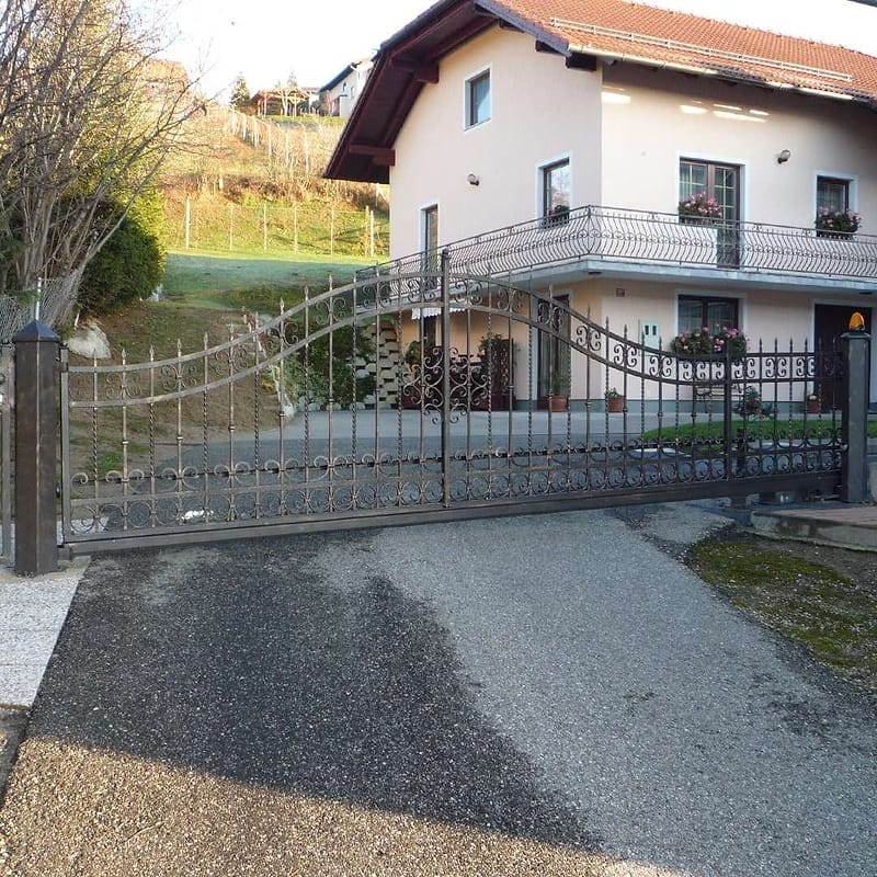 Kovinska dvoriščna vrata in ograja pred stanovanjsko hišo