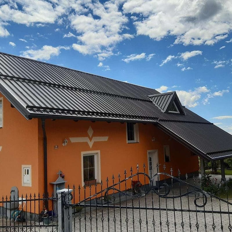 Stanovanjska hiša s temno pločevinasto streho in žlebovi