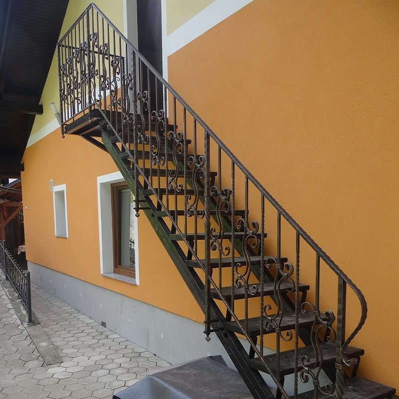 Zunanje kovinske stopnice z ograjo ob fasadi hiše